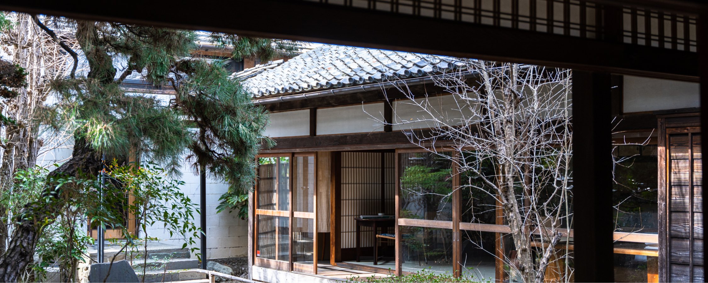 Traditional tiled-roof entrance to the brewery's main house, framed by a pine tree.