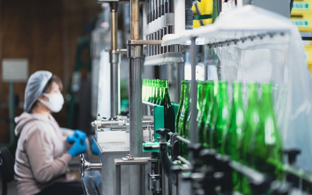 A worker operates the bottling line where sake is filled and capped.