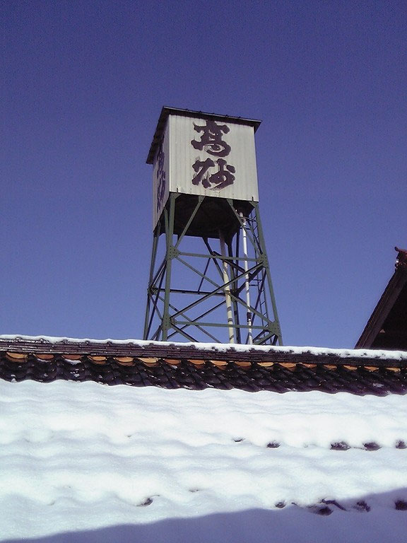 The brewery's rooftop water tower bearing the Takasago sign, seen under a winter sky.