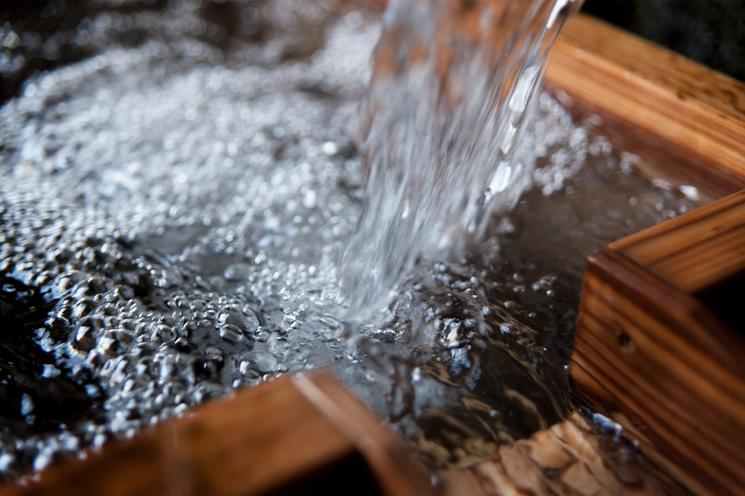 Natural spring water, the source of the brewery's soft water, pouring into a wooden vessel.