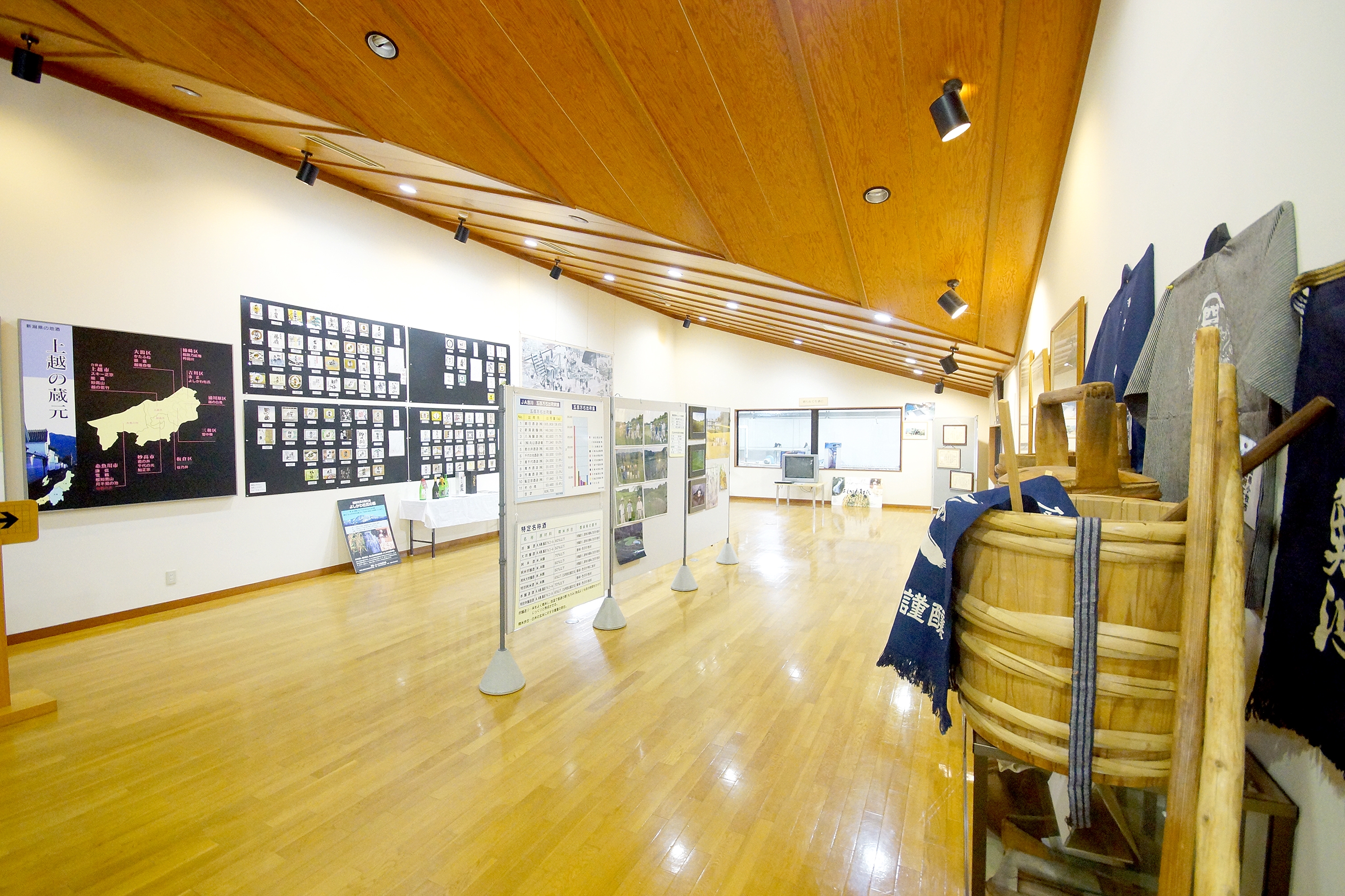 History and archive space (2F) displaying regional sake-brewing records and toji happi coats
