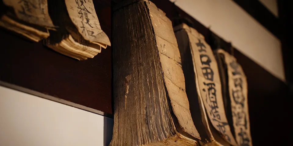 Close-up detail of old wooden sake labels hanging from a beam inside the brewery.