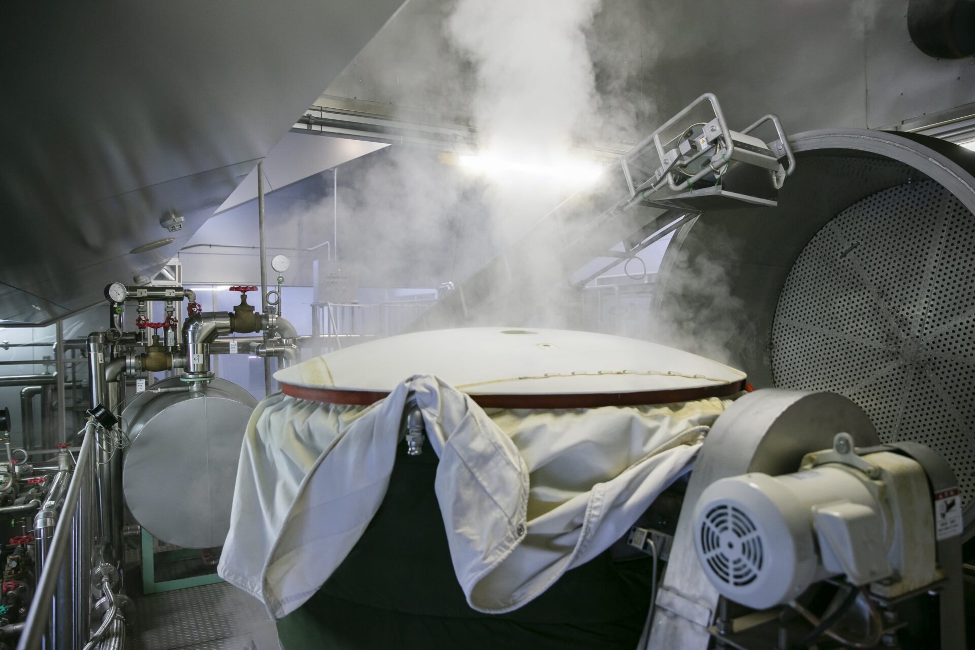 Steam rising from a rice steaming vat inside the brewing facility.