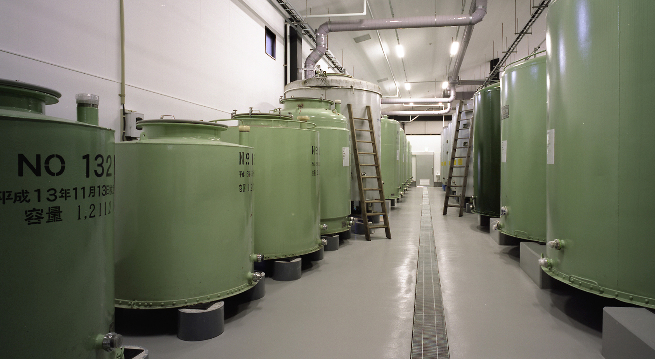 Rows of green fermentation tanks inside the brewery's storage hall.