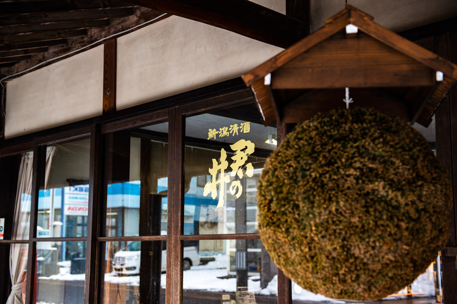 Entrance of the historic storefront with a suspended sugidama cedar ball and gold shop signage.