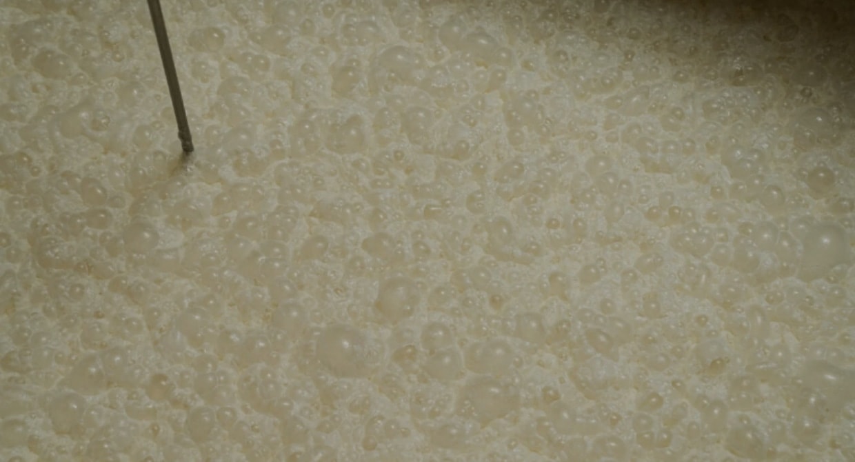Close-up of fermenting moromi mash bubbling in a tank.