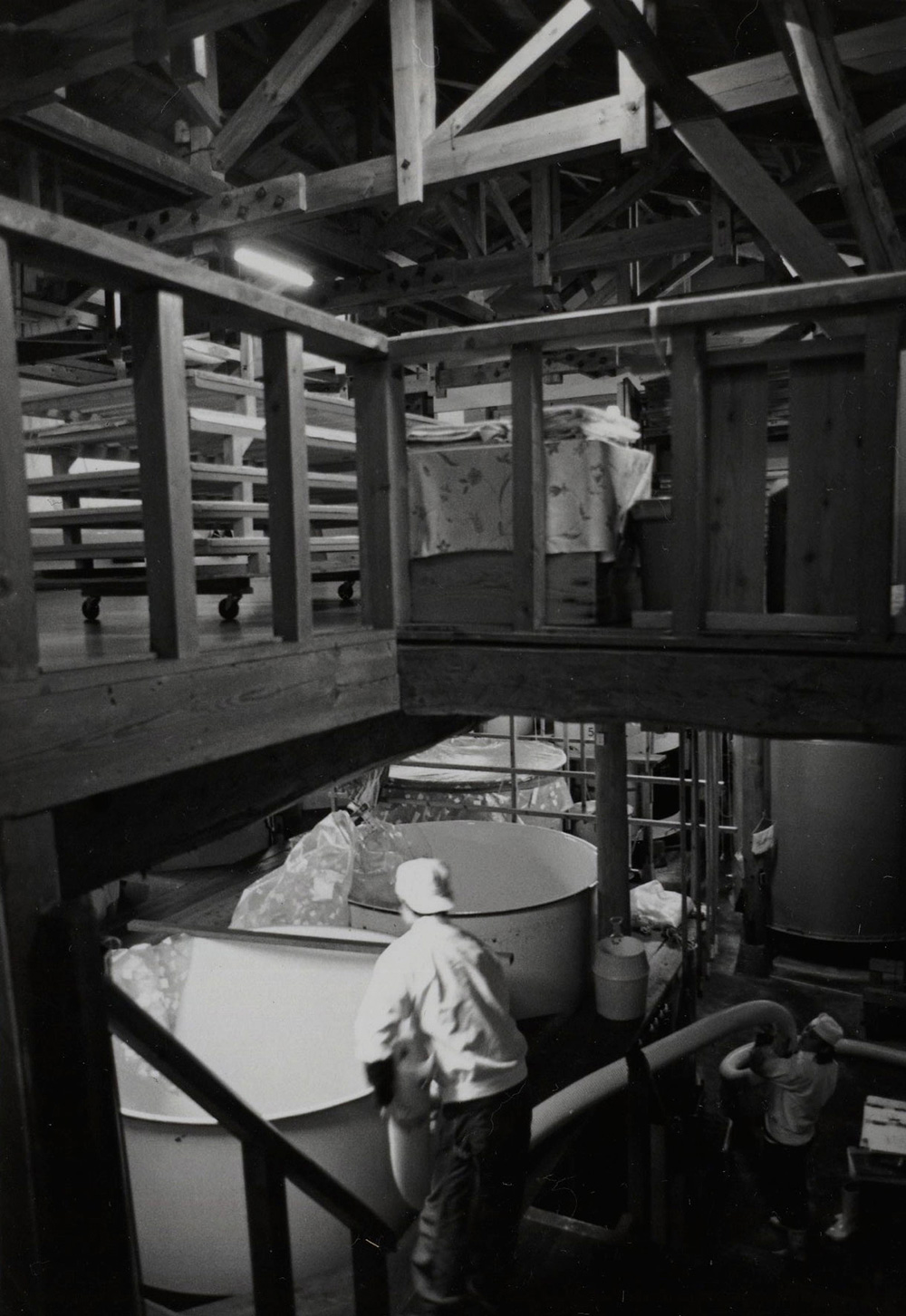 Inside the wooden brewery, brewers work around large fermentation vats and rice-cooling equipment.