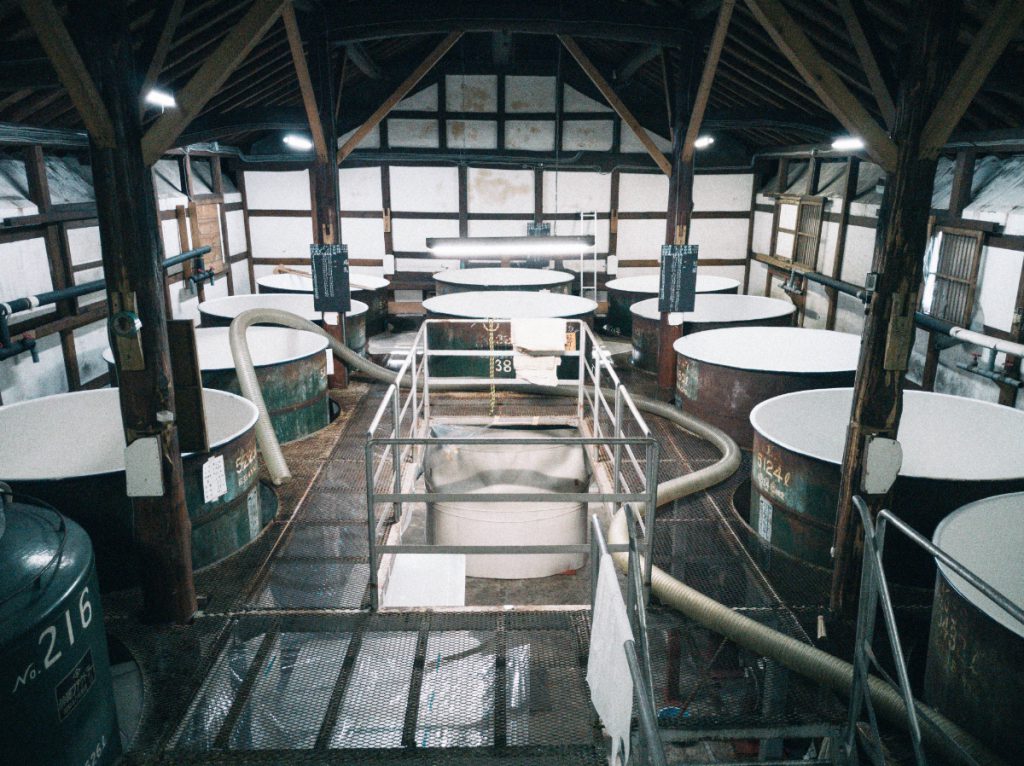 Rows of fermentation tanks inside the century-old wooden brewing hall where the moromi mash is fermented.