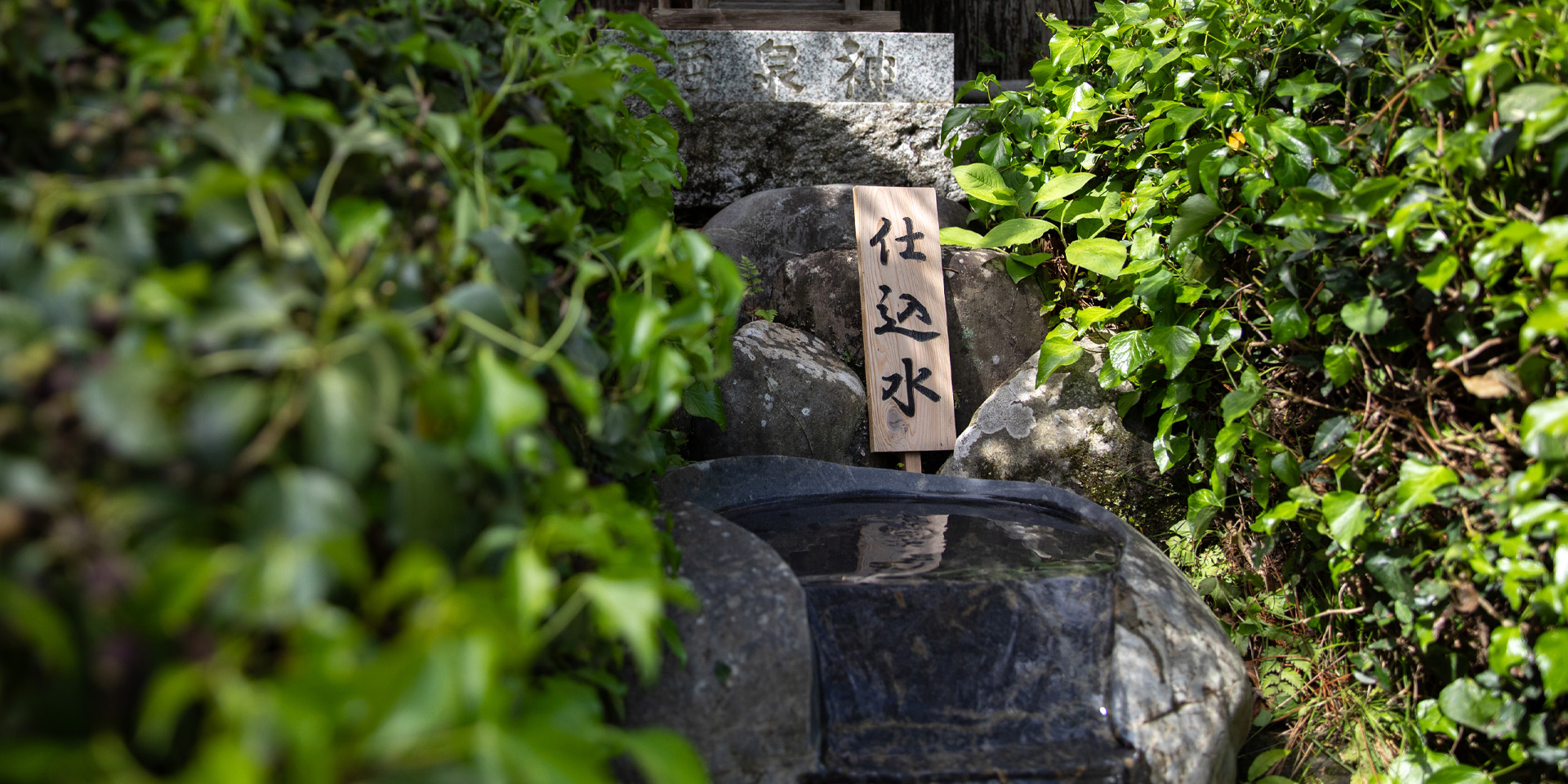 Stone-carved spring on the brewery grounds marking the brewing water source (仕込水)