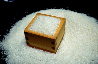 A wooden masu box filled with the brewery's carefully selected rice.