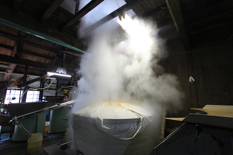 Steam rising during the steaming of rice inside the brewery.