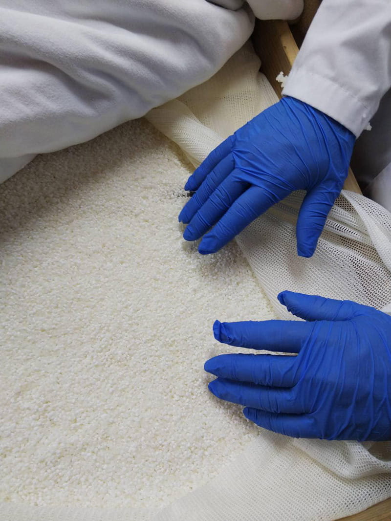 Close-up of freshly steamed rice being handled during the brewing process