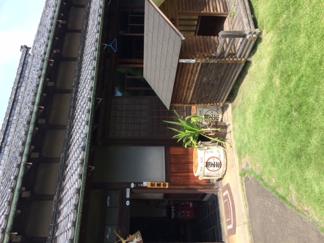 Side exterior of the brewery building with sake barrels and the brewery dog's kennel