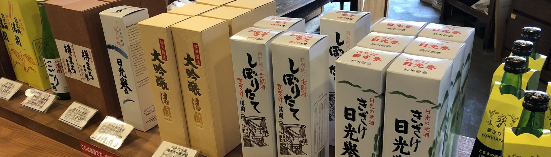 Interior view of the brewery's retail shop with sake and shochu boxes on display.