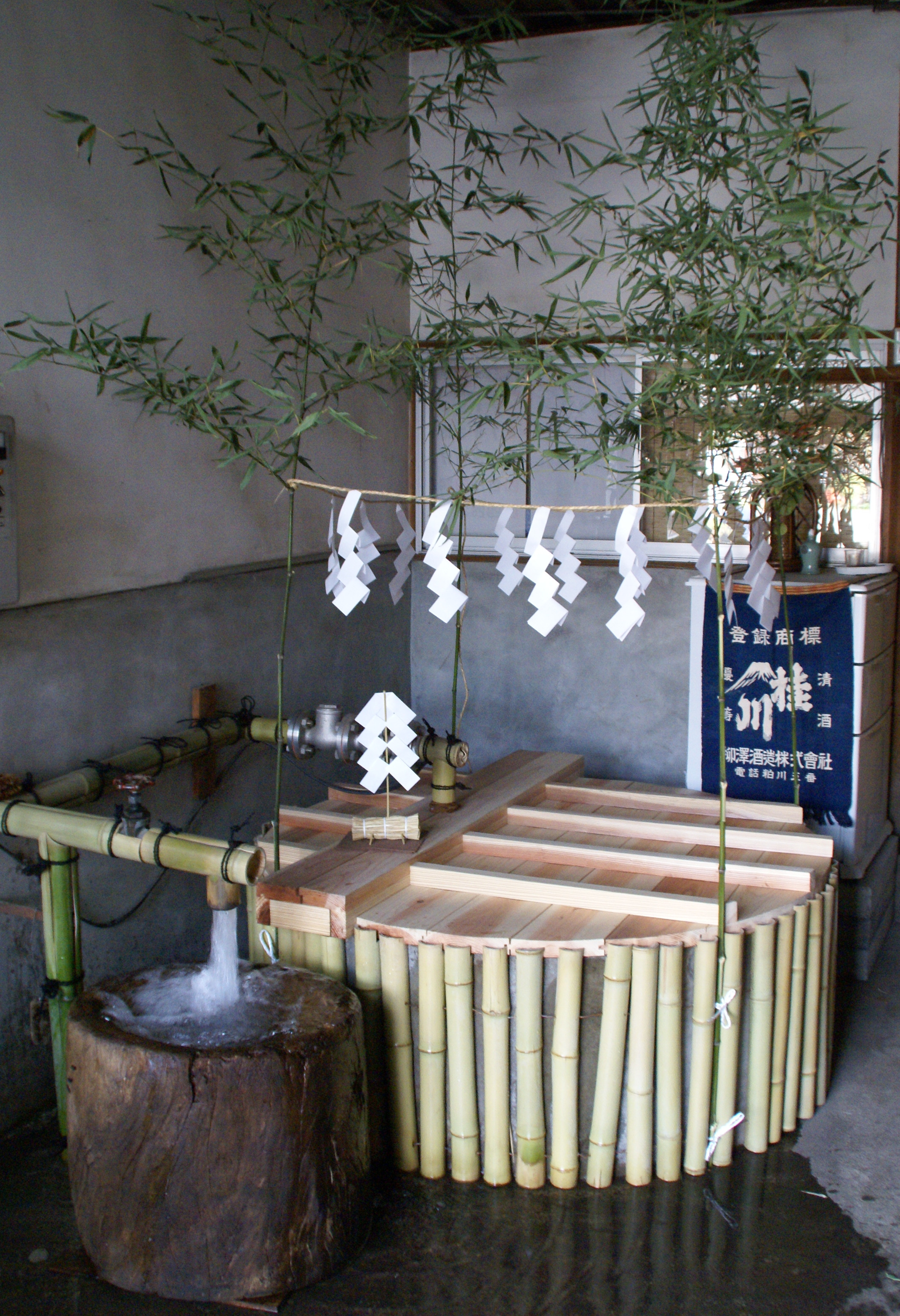 Ceremonial water-drawing setup with a Katsuragawa brewery banner in the background