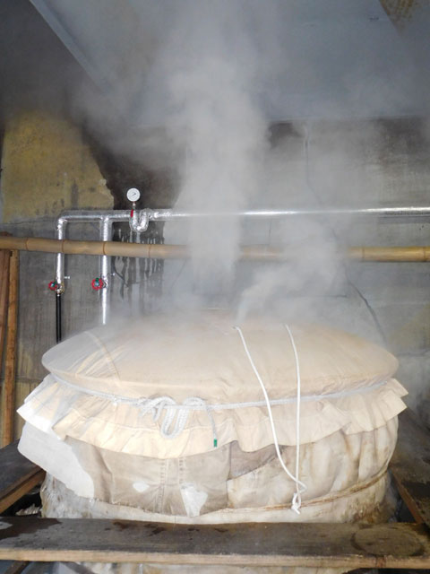Steaming rice mash (moromi) wrapped in cloth during the brewing process