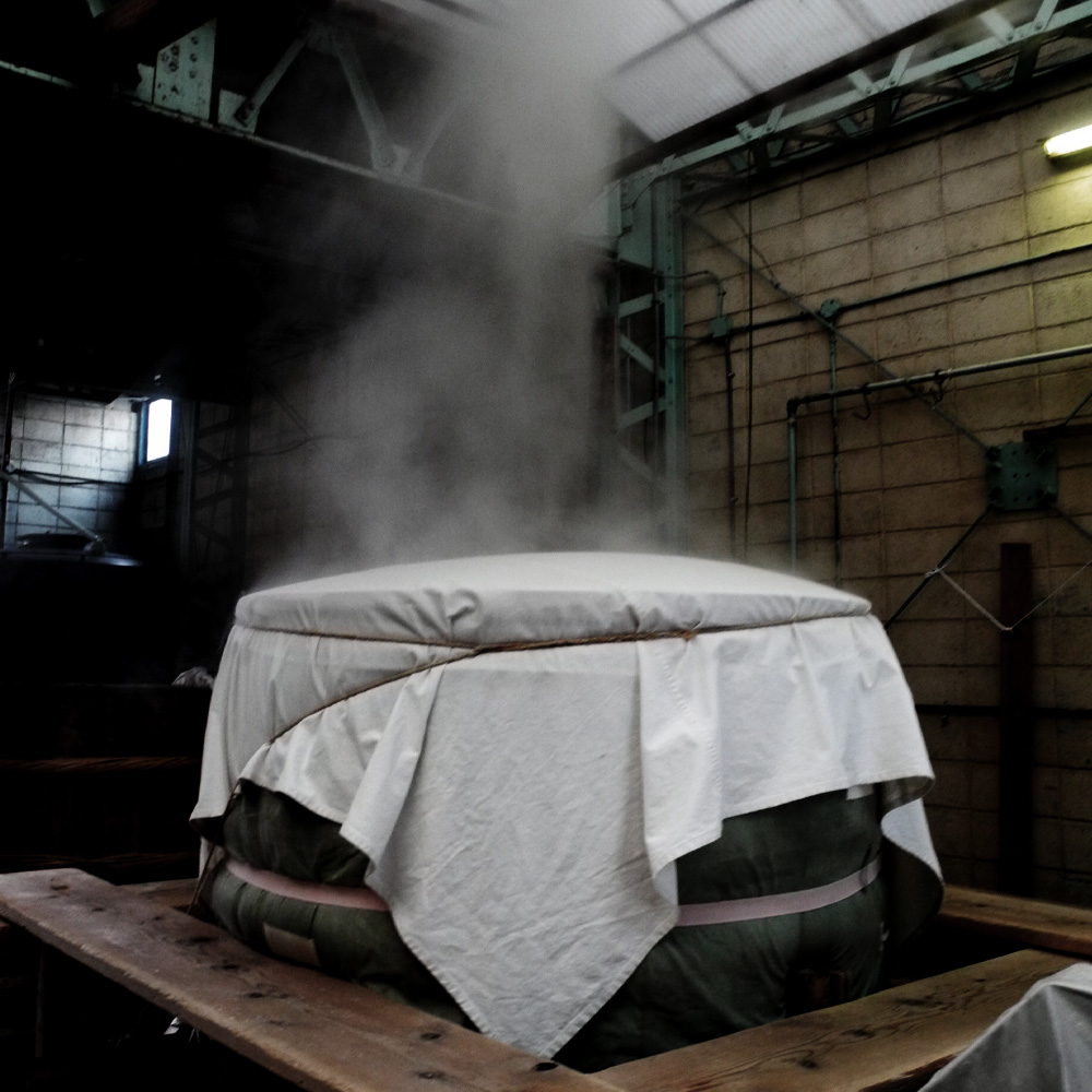 Steam rising from a cloth-covered rice-steaming vat (koshiki)