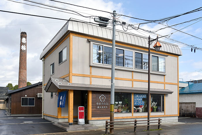 Exterior of the brewery's direct-sales shop, with the brick chimney marked 香梅 in the background