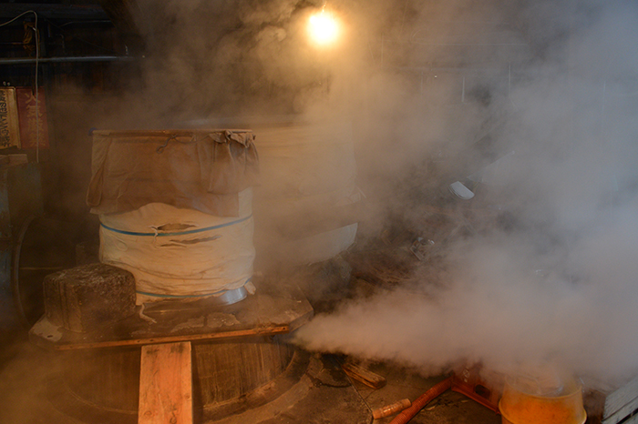 Steamed rice being cooled amid rising steam in the brewery