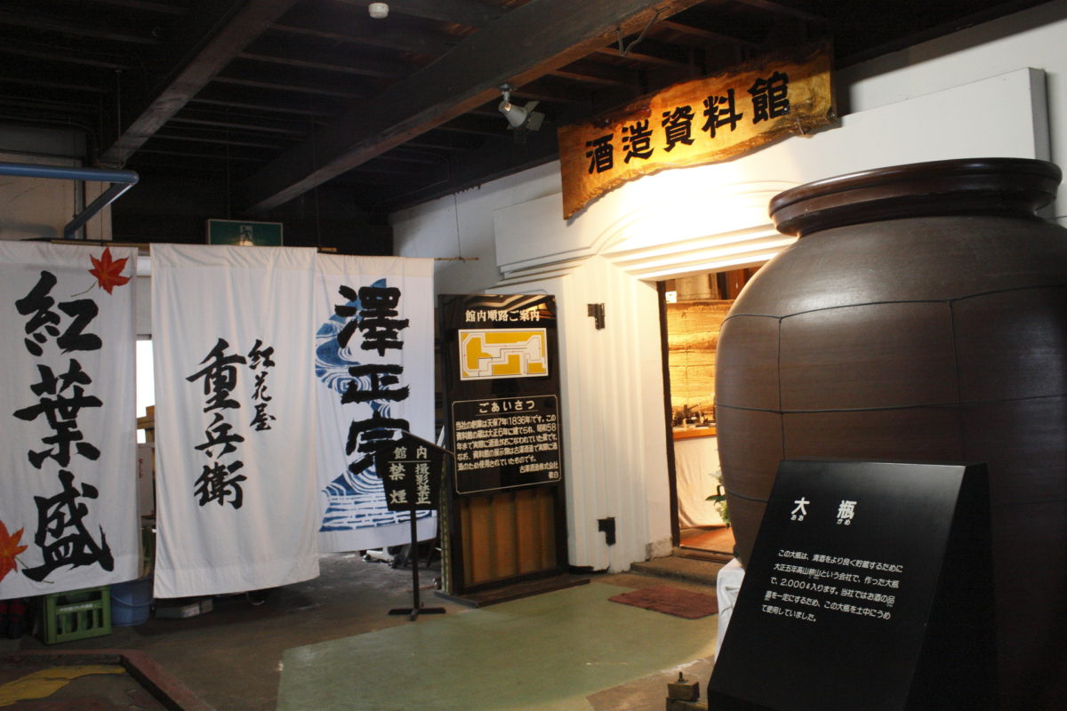 Entrance to the brewery's sake history museum, hung with noren curtains bearing the Sawamasamune and Benibanaya Juubee brand names.