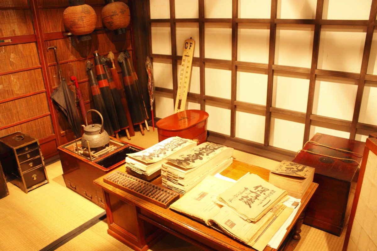 A preserved tatami room inside the museum displaying historic brewery ledgers and tools.