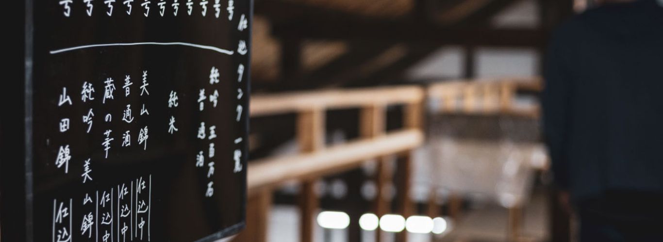 Inside the brewery, a board lists the rice varieties and tank contents used for brewing.