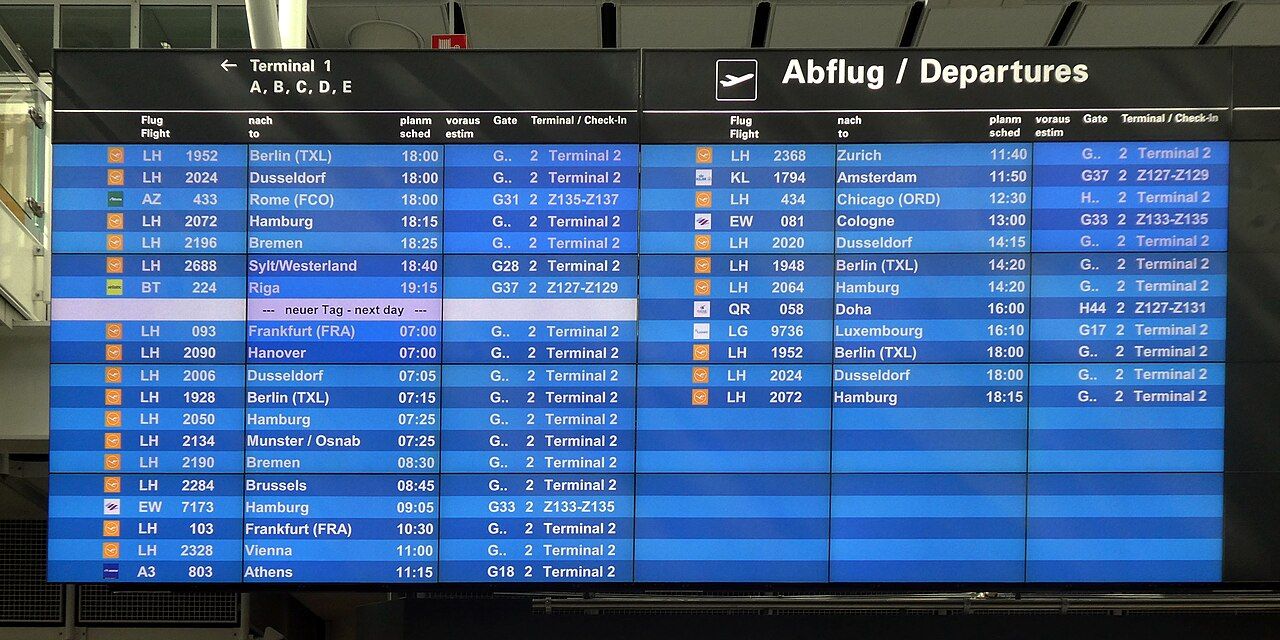 Airport departure board showing Lufthansa flights to various cities. Focus is on destinations, flight numbers, and times.
