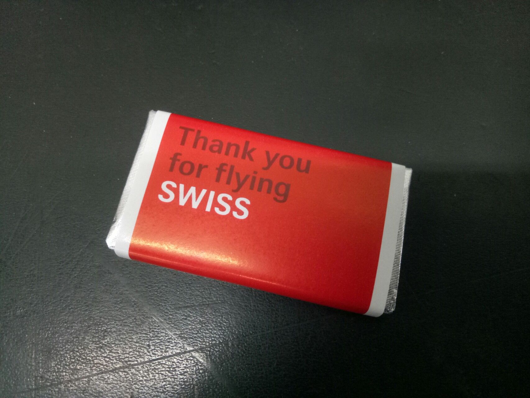 A small SWISS chocolate bar on a dark surface.