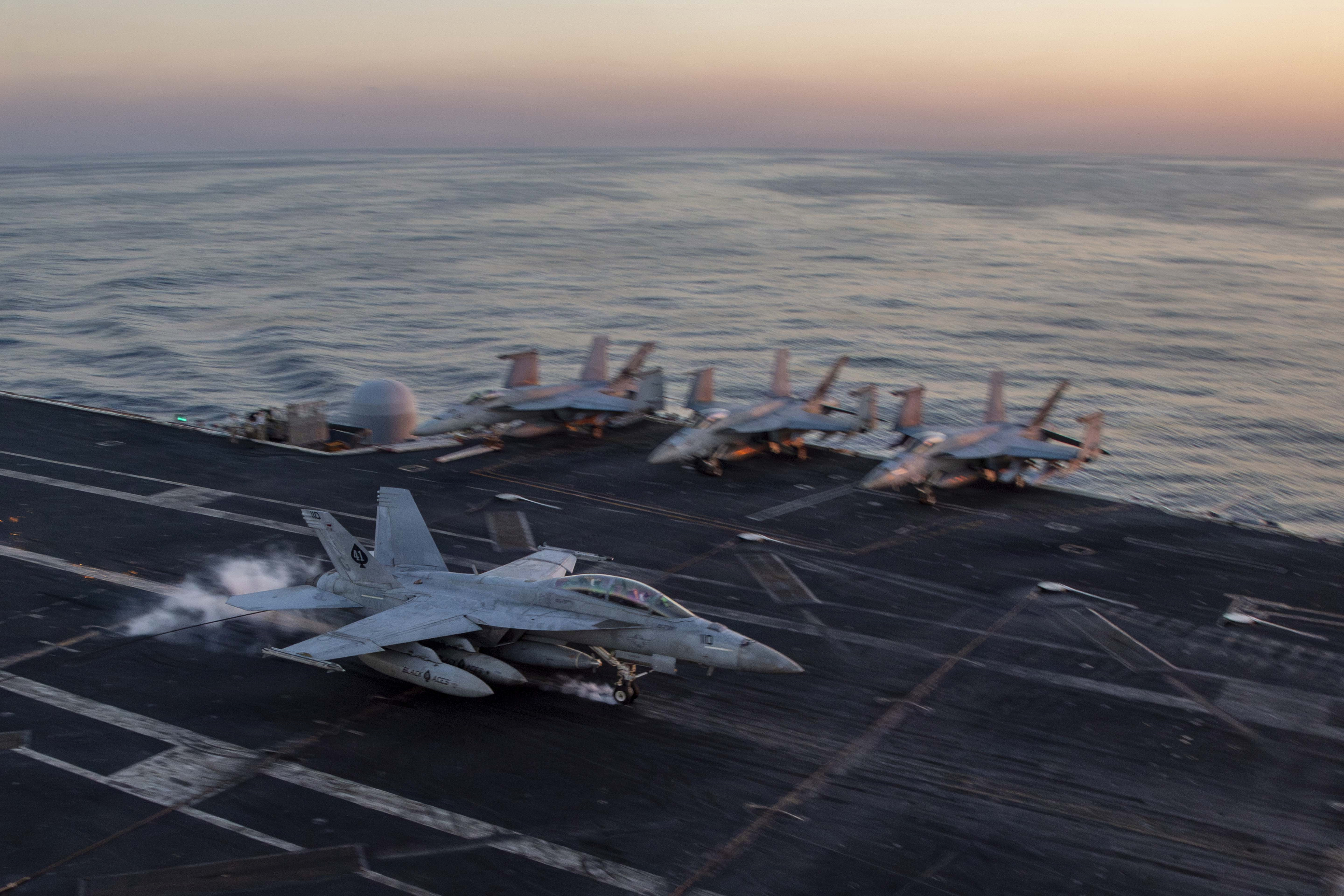 Jet landet bei Sonnenuntergang auf einem Flugzeugträger