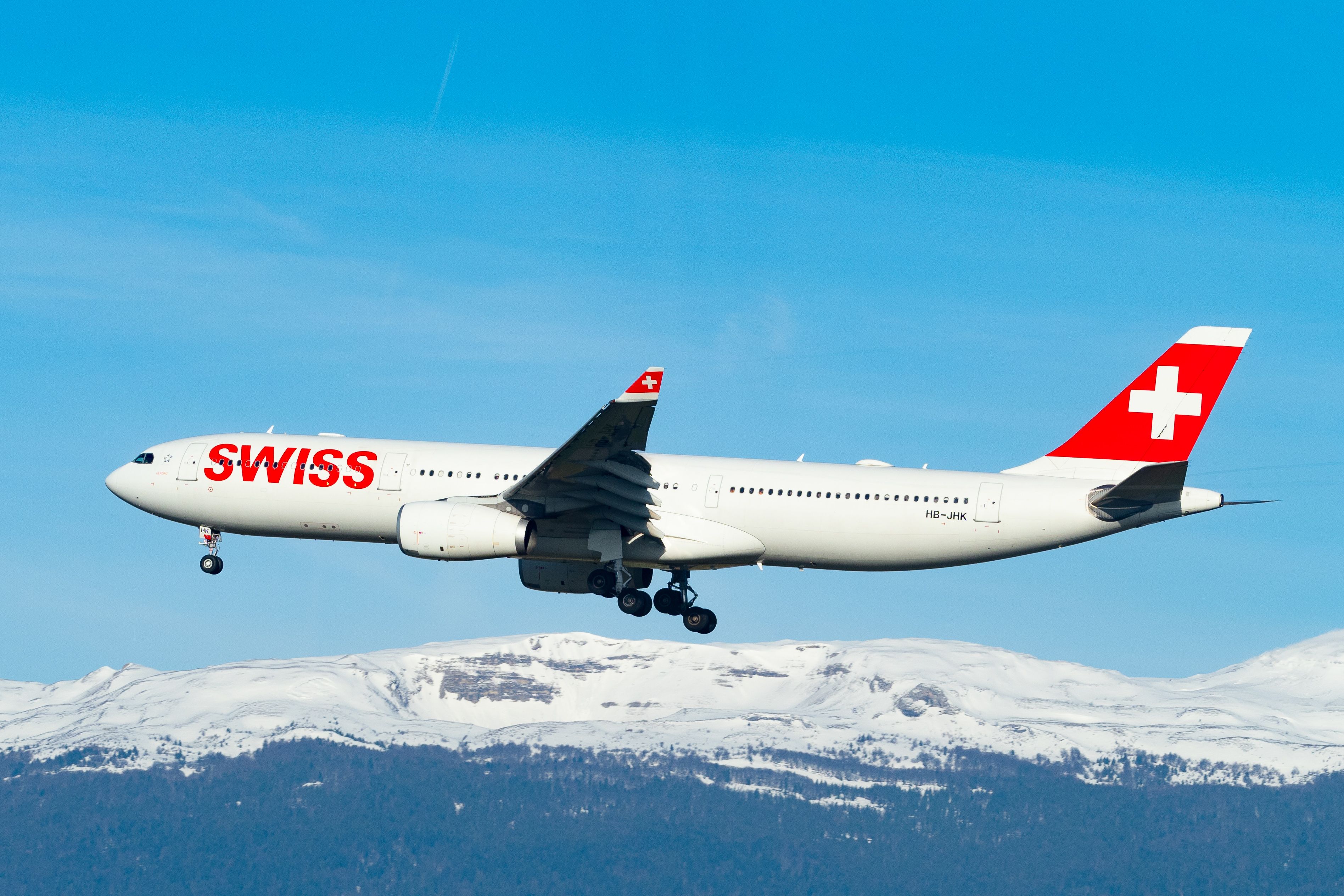 SWISS Airbus A330-300 (HB-JHK) descending over snow-capped mountains in 2019 with landing gear extended.