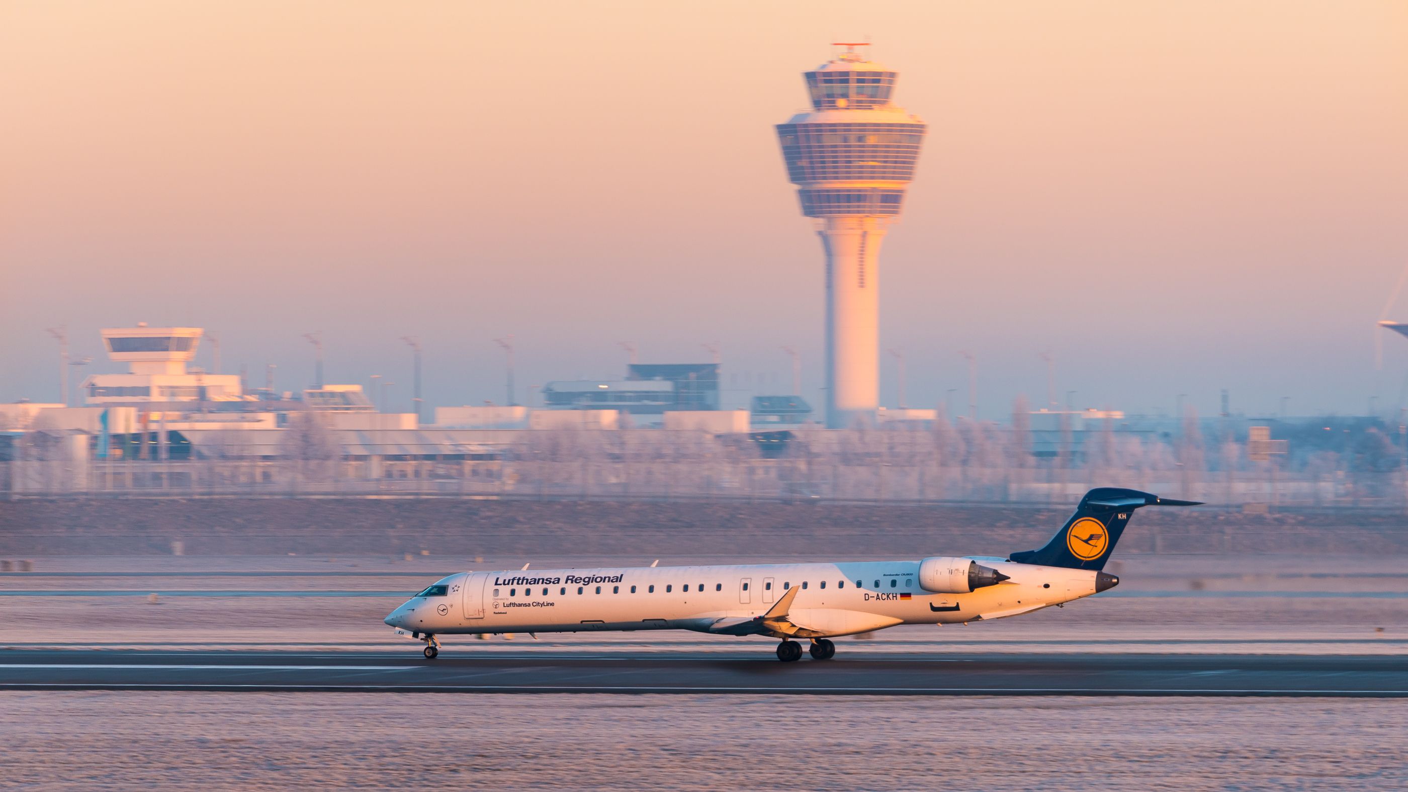 Eine Lufthansa CityLine CRJ-900LR mit der Kennung D-ACKH startet im Morgengrauen vom Flughafen München.