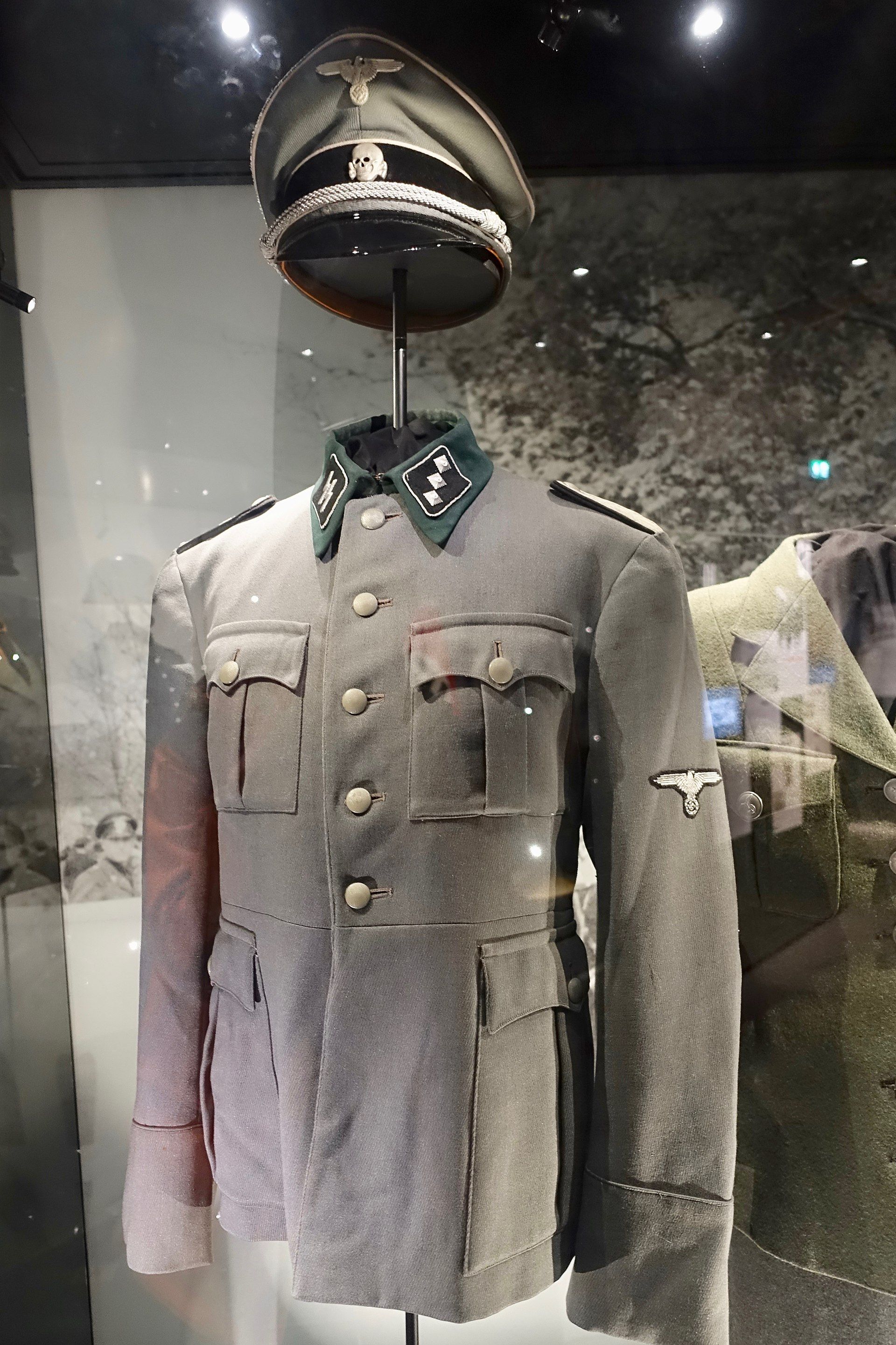 A SS uniform on display in a museum case, highlighting the historical ties between Hugo Boss and the Nazi regime.
