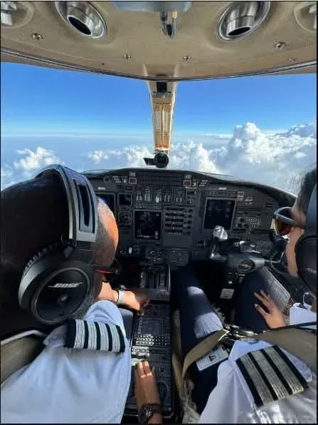 Pilots in a private jet cockpit above the clouds