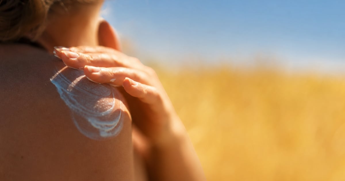 Sonncrème-Tub op engem faarwege Handduch, mëllt Summerliicht