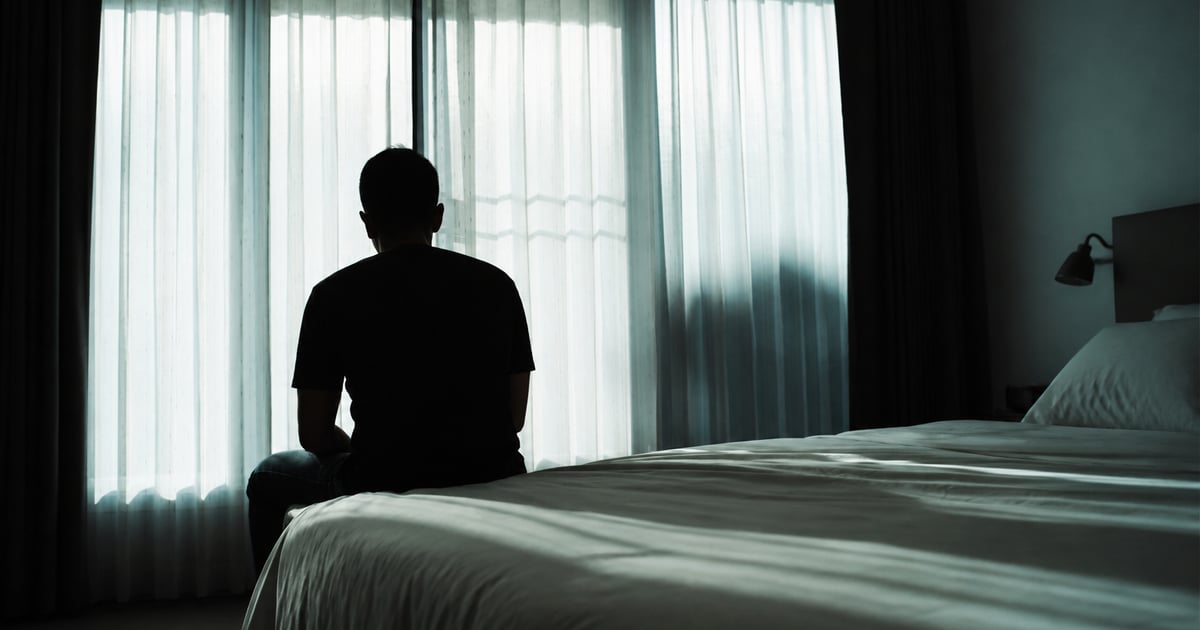 Un adolescent privește pe fereastră, pierdut în gânduri, lumină blândă