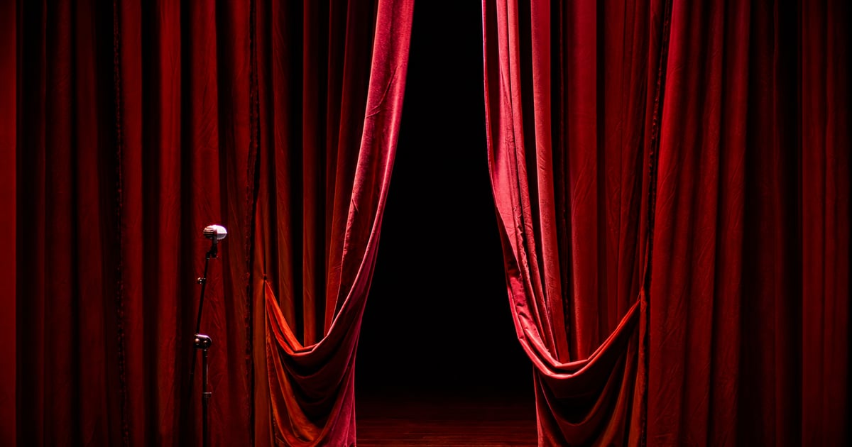 Red curtain slightly open, stage lights and the shadow of someone about to step on stage