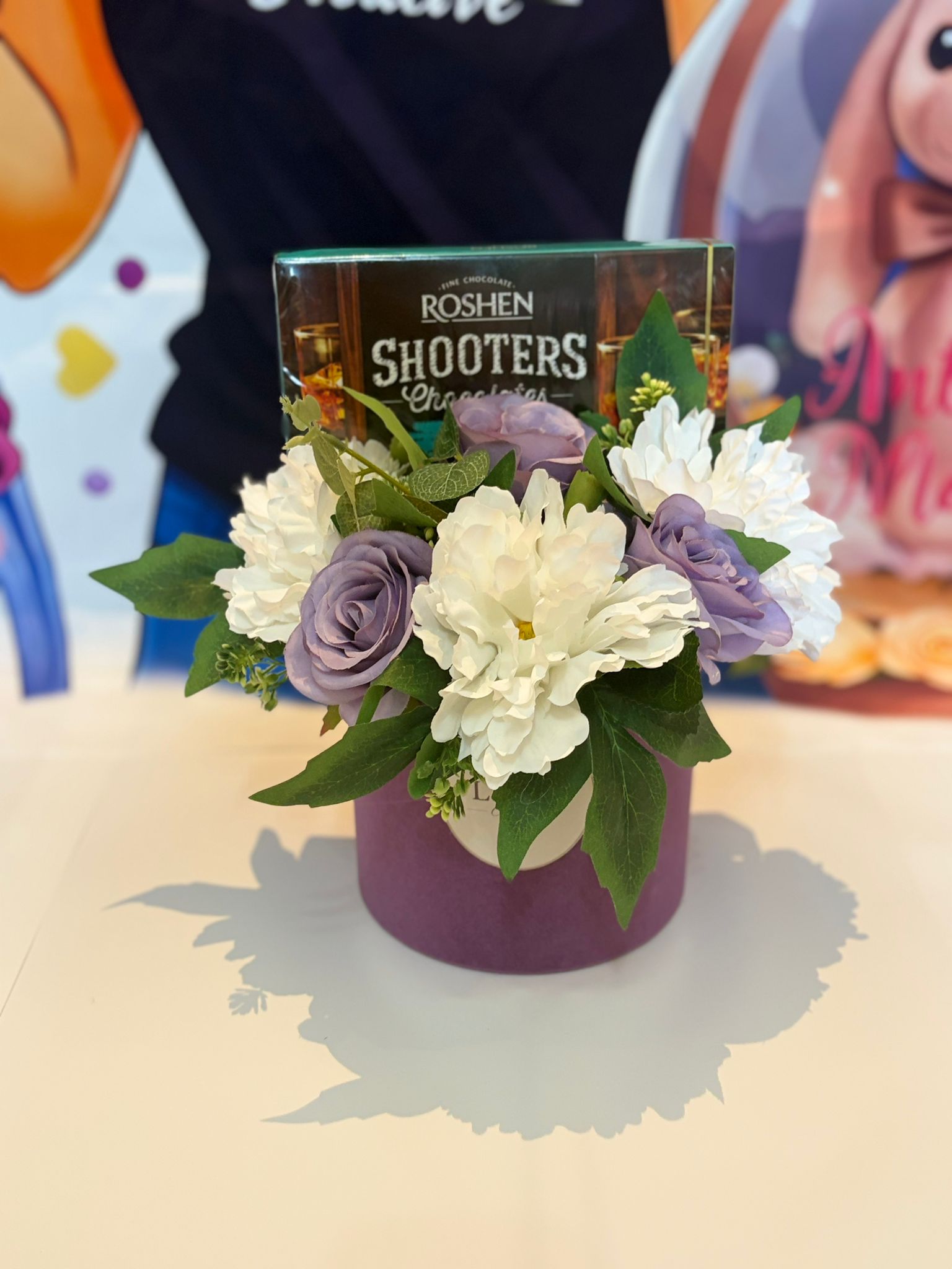 Aranjament floral în cutie lila cu flori albe, violet și cutie de bomboane
