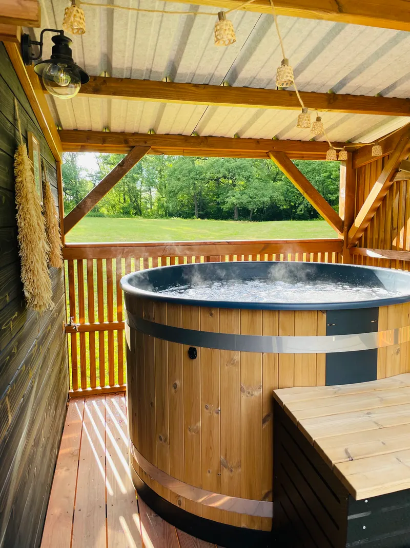 Bain nordique en bois sur une terrasse entourée de forêt