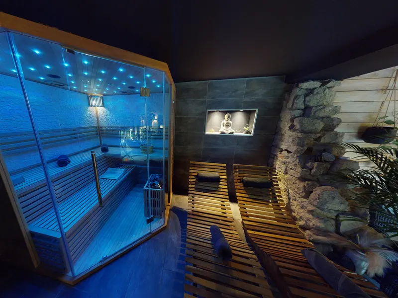 Sauna privatif en bois éclairé en bleu dans une suite romantique