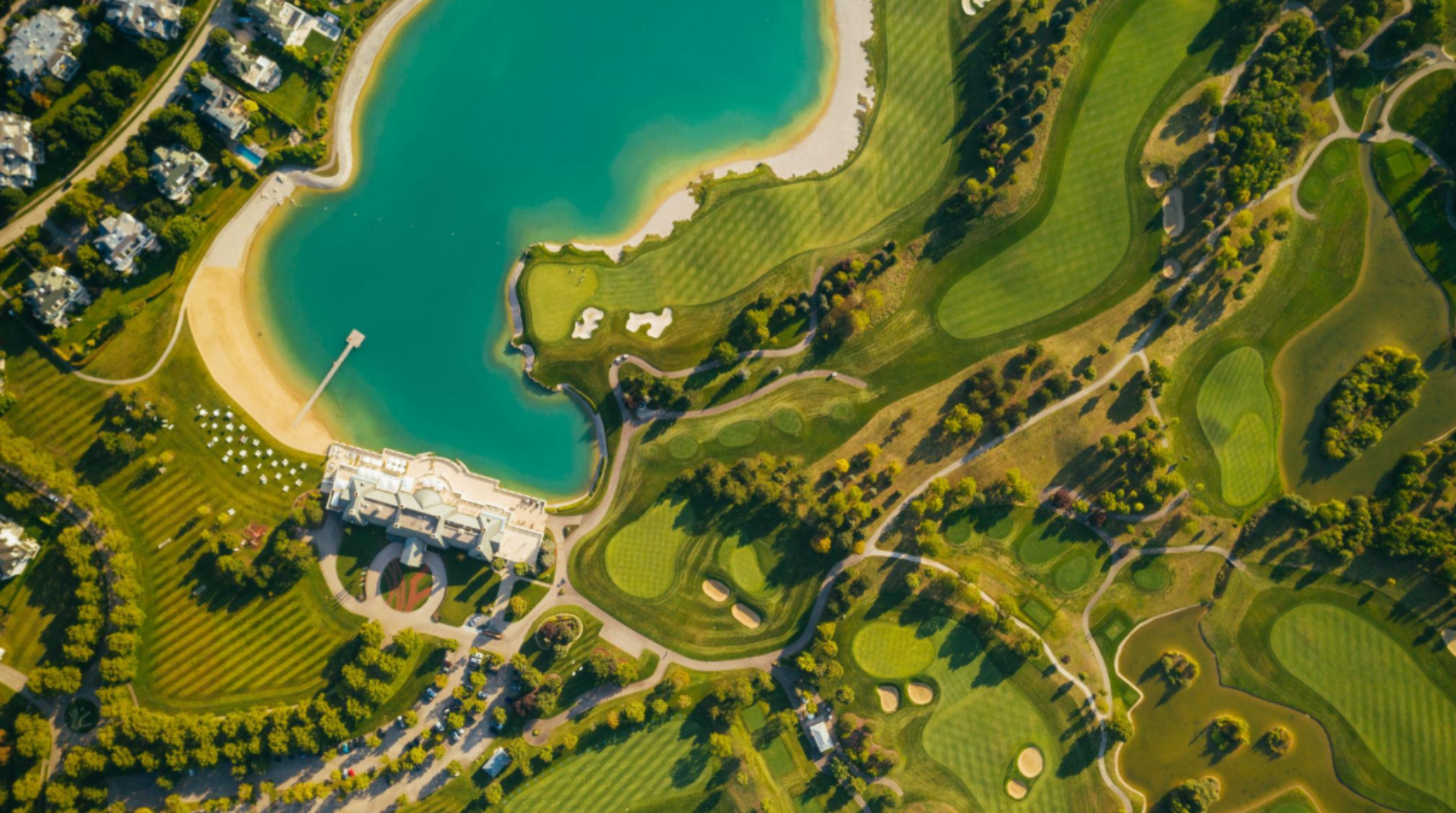 Golf Privé & Slow Luxury : Nouvelle SignaturVue aérienne d’un domaine de golf de luxe avec lac, villas et parcours paysager, illustration d’un resort immobilier haut de gammee du Luxe Moderne, Investissement et Capital Relationnel