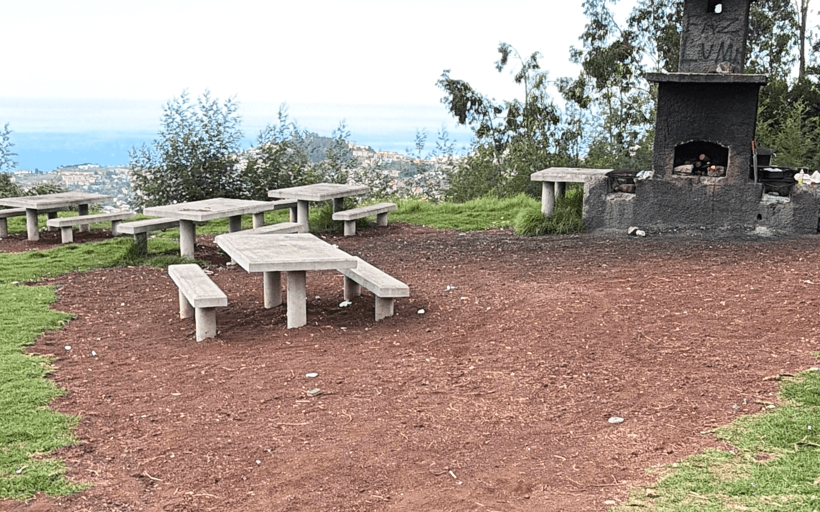 Stone picnic tables and built-in barbecue at Parque de Merendas do Galeão overlooking Funchal