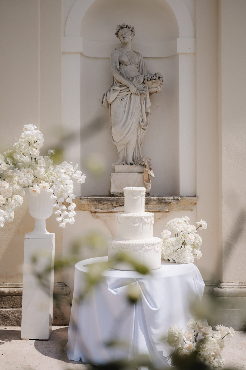 Prachtvolle mehrstöckige Hochzeitstorte mit weißen Blumen in italienischer Villenlocation