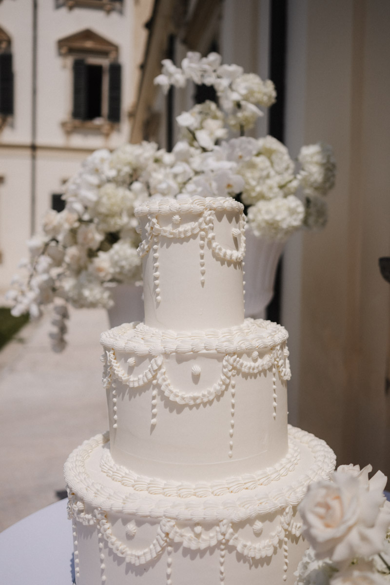 Mehrstöckige weiße Luxus-Hochzeitstorte mit kunstvollen Blumen und eleganter Dekoration