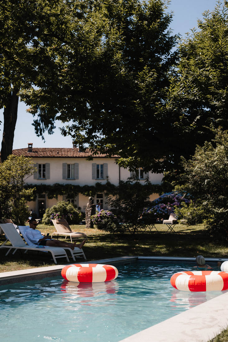 Pool mit roten Schwimmringen und Personen bei einem Haus mit Garten