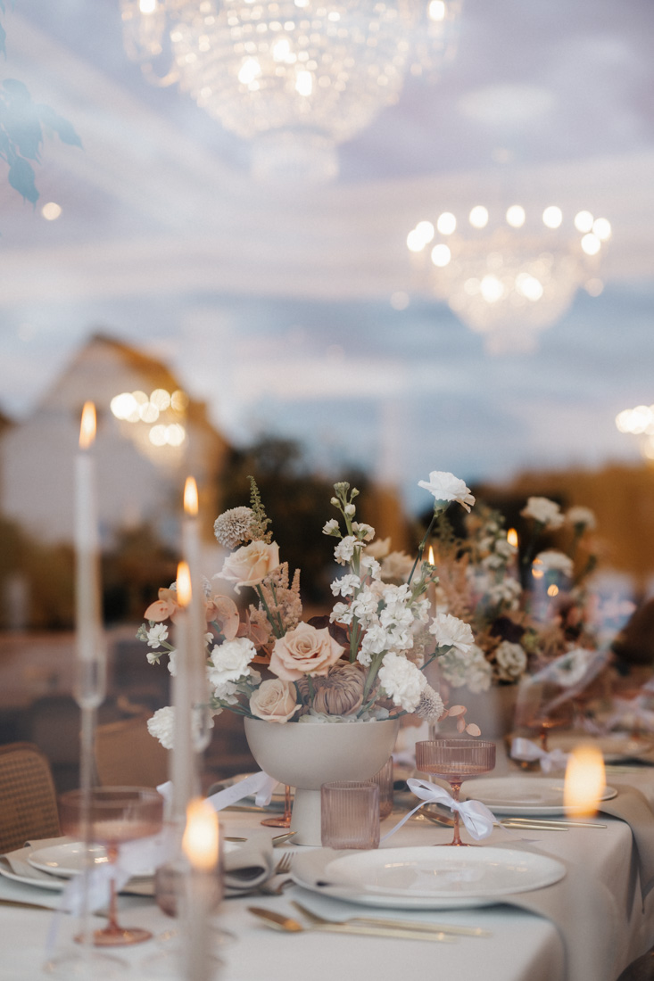Gedeckter Tisch mit Blumen in Schale und Kerzen mit Kronleuchter