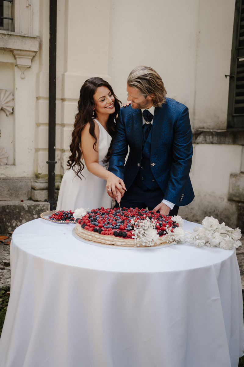 Brautpaar schneidet gemeinsam elegante Beerentorte bei Hochzeitsfeier an