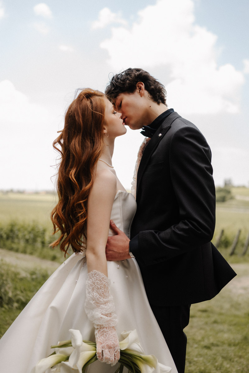 Braut und Bräutigam küssen sich bei romantischer Outdoor-Hochzeit im natürlichen Licht