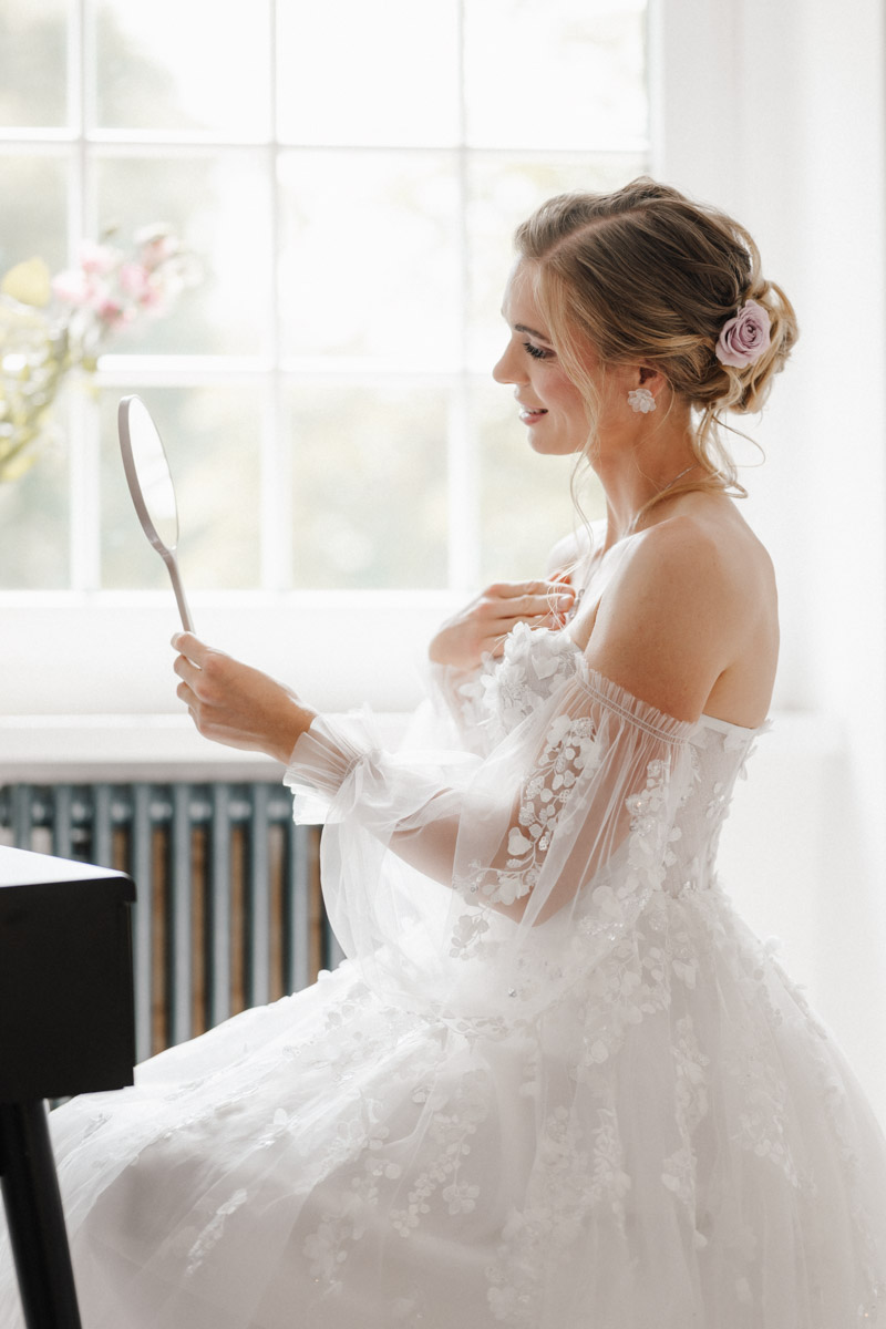 Frau im weissen Kleid mit Spiegel und Blume im Haar