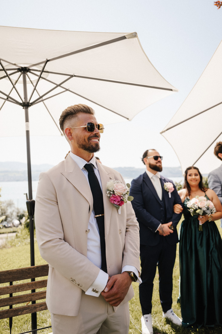 Mann im Anzug mit Sonnenbrille und Blumenschmuck bei Zeremonie