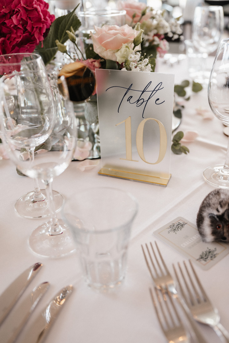Tischdekoration mit Blumen Gläsern und Tisch Nummer Zehn